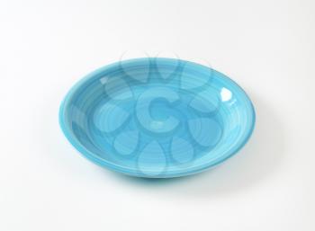 Coup shaped ceramic plate with a blue color glaze