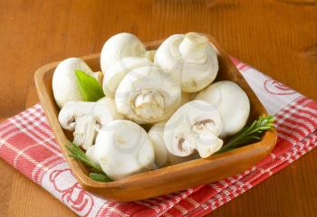 Fresh button mushrooms in square wooden bowl