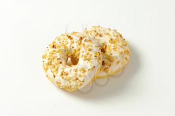 Two maple-glazed ring donuts topped with chopped nuts
