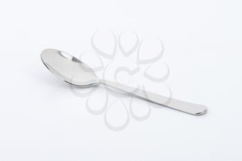empty metal spoon on off-white background