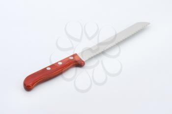 bread knife with wooden handle on off-white background