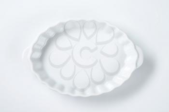empty oval fluted white casserole dish