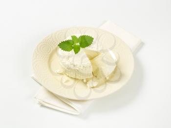 wheel of fresh curd cheese on plate