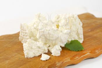 pieces of fresh curd cheese on cutting board