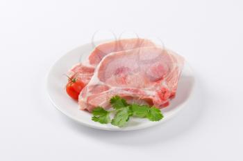 raw pork chops on white plate