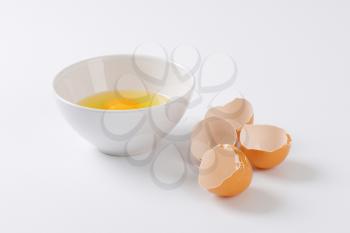 cracked eggs in a bowl and empty eggshells next to it