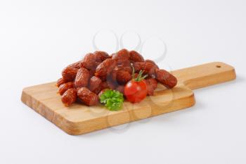 strings of mini cabanossi sausages on wooden cutting board