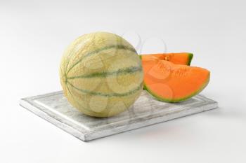 fresh cantaloupe melon on wooden cutting board