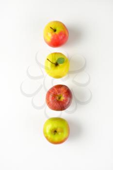 four ripe apples in a row on white background