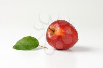 washed red apple with leaf on white background