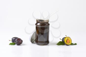 jar of thick plum butter and fresh plums next to it