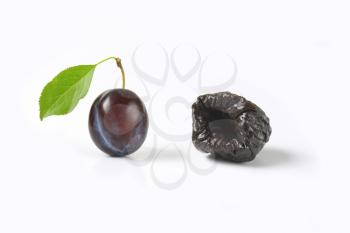 one fresh plum and one prune on white background