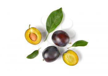 ripe plums with leaves on white background
