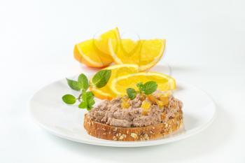 Whole grain bread with meat spread and pieces of candied orange rind