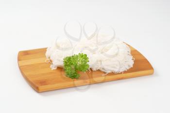 cooked rice noodles on wooden cutting board
