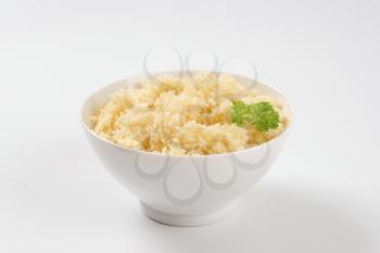 bowl of cooked couscous on white background
