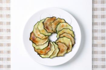 circle of thin slices of roasted zucchini on a white plate