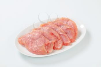 Raw turkey breast escalopes on plate