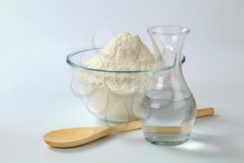 white wheat flour in a glass bowl and a carafe of cold water