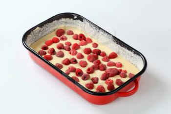 raw cake batter with frozen raspberries in baking tray ready to be baked