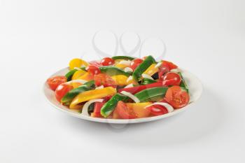 Plate of fresh bell pepper strips and halved cherry tomatoes