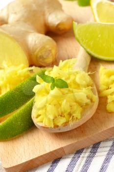grated fresh ginger root with lime on wooden cutting board