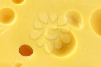 full frame background of yellow cheese with holes
