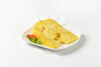 wedge of medium-hard Swiss cheese on white plate