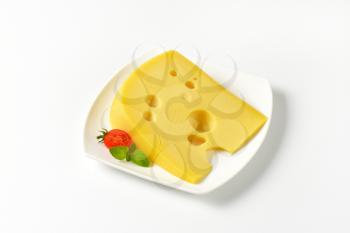 wedge of medium-hard Swiss cheese on white plate