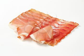 Thin slices of dry-cured smoked ham (Schwarzwald ham) on white background