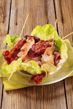 Grilled chicken skewers and bacon served on lettuce leaves
