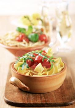 Ribbon pasta and diced tomato topped with arugula