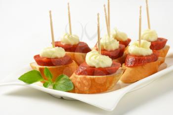 Bread based canapes with spicy sausage and creamy spread