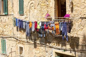 Weathered facades of residential houses in Italian Volterra with laundry drying on clothes lines