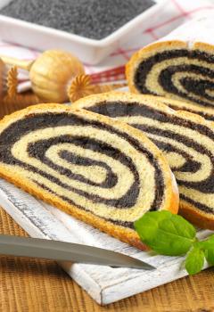 close up of sliced poppy seed roll on wooden cutting board
