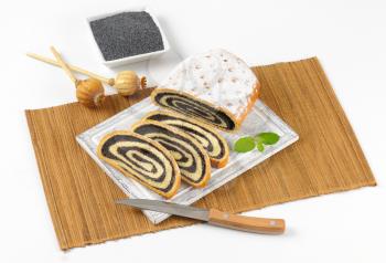 bowl of poppy seeds and sliced poppy seed roll on wooden cutting board