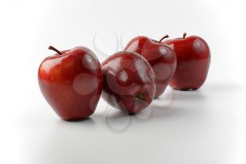 four glossy red apples in a row
