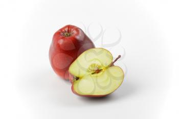One and a half red apples on off-white background