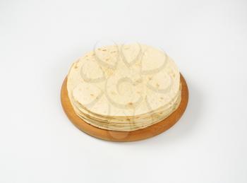 stack of flour tortillas on wooden cutting board