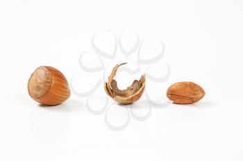 whole and cracked hazelnuts on white background