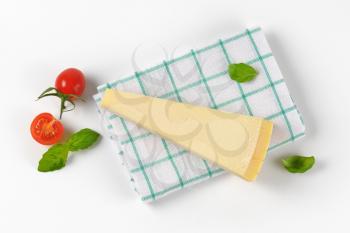 wedge of fresh parmesan cheese and cherry tomatoes on checkered dishtowel