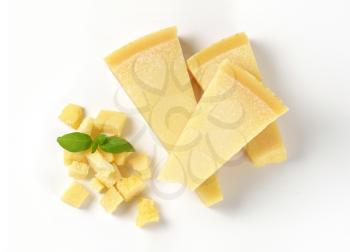 wedges and pieces of parmesan cheese on white background