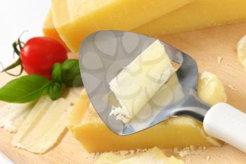 close up of cheese knife on parmesan cheese