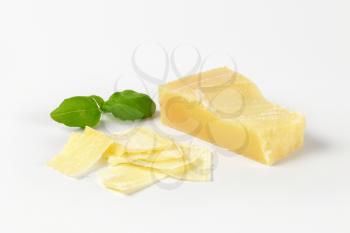 sliced parmesan cheese and basil on white background