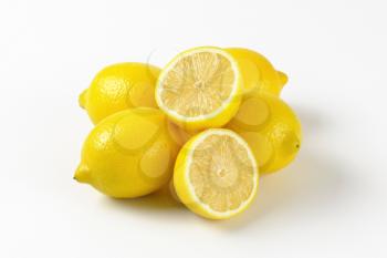 whole and halved ripe lemons on white background