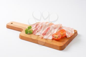 Thin slices of fresh streaky bacon on cutting board