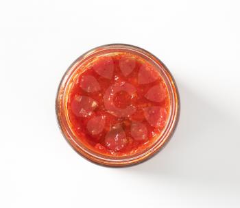 jar of tomato based pesto sauce on white background
