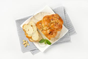 sliced loaf of sweet braided bread with almonds and raisins on white plate