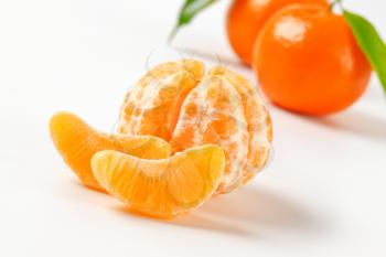peeled and unpeeled tangerines on white background