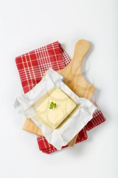 unwrapped block of fresh butter on wooden cutting board